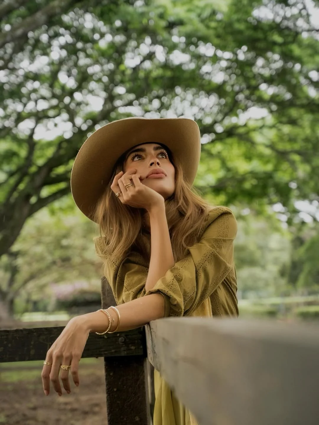 Modelo ELÓR con sombrero Austin Sun Hat apoyada en valla de madera, mirada contemplativa